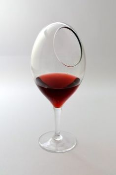 a glass filled with red wine sitting on top of a table