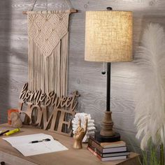 a desk with a lamp, books and some decorations on it in front of a wooden wall