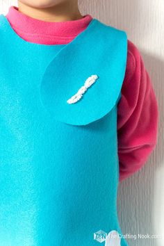 a close up of a doll wearing a blue sweater with a pink shirt on it