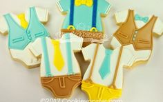 decorated cookies in the shape of baby clothes and vesters are arranged on a table