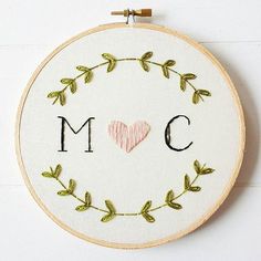 a cross stitch pattern with the letter m c and a heart surrounded by green leaves