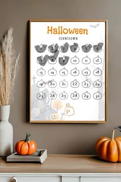 a halloween calendar is hanging on the wall next to some pumpkins and a vase