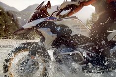 a man riding on the back of a motorcycle through water