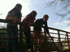 three young people are standing on a bridge