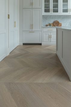 a kitchen with white cabinets and wood floors