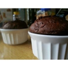 two chocolate muffins sitting on top of a wooden table