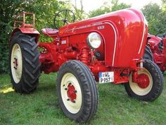 an old red tractor parked in the grass