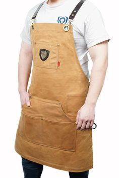 a man wearing an apron and holding his hands in his pockets while standing against a white background