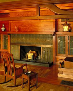 a living room filled with furniture and a fire place next to a wooden floored wall