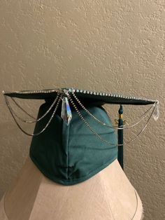 a green hat with chains attached to it's sides and a tassel on top