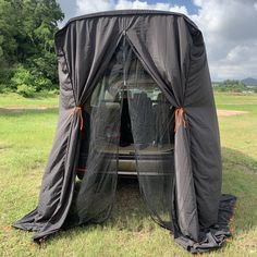 a car covered in black tarp sitting on top of a lush green field