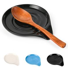 three wooden spoons sitting on top of a black plate next to two blue and white plates