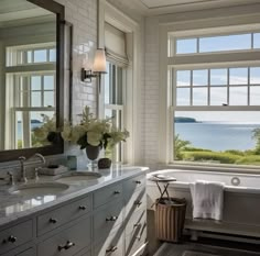 a bathroom with two sinks and a large window overlooking the water in front of it