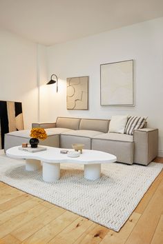 a living room with a couch, coffee table and rug on the wooden flooring