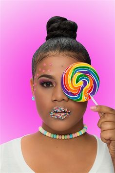 a woman holding a lollipop in front of her face with sprinkles on it