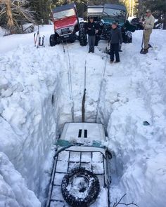 two men standing in the snow next to some vehicles