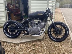 a black motorcycle parked in front of a garage