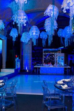 an indoor event venue with blue lighting and chandeliers hanging from the ceiling