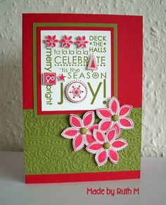 a handmade card with pink flowers and green trimmings on the bottom, in front of a white wall