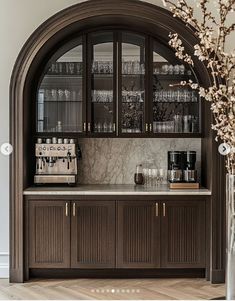 an arched doorway leads to a bar with wine glasses on it and a coffee maker in the corner