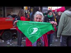 an older woman holding up a green kite