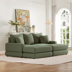 a living room with a large green couch and white rugs on the wooden floor