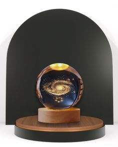 an image of a glass ball with a galaxy in it on a wooden stand against a black background