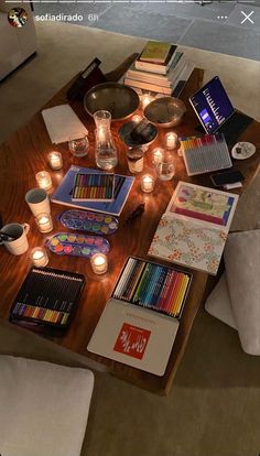 a living room filled with lots of books and art supplies on top of a wooden table