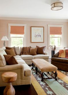 a living room filled with lots of furniture next to a window covered in shades of brown and tan