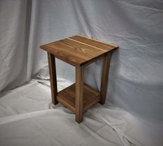 a small wooden table sitting on top of a white sheet