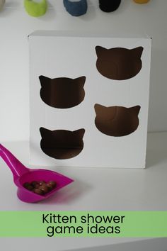 a pink spoon sitting in front of a box with cut out cats on it and the words kitten shower game ideas