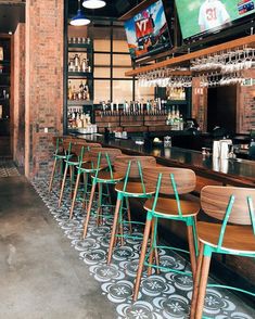 a bar with wooden chairs and televisions on the wall