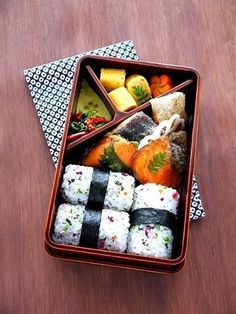 a bento box filled with different types of sushi on top of a wooden table