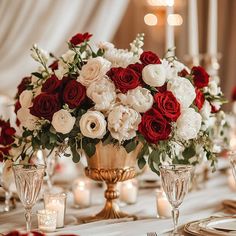 a vase filled with red and white flowers on top of a table next to candles