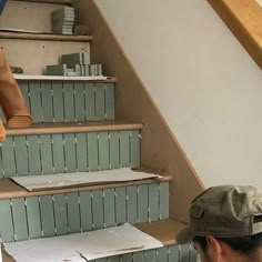 a man is sitting on the stairs in front of some shelves with books and papers