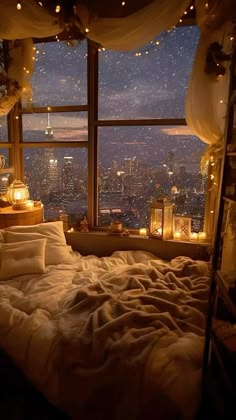 a bedroom with a large window overlooking the city lights and candles on the windowsill