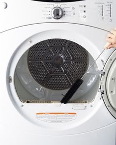 a person is using a brush to clean the front of a washing machine