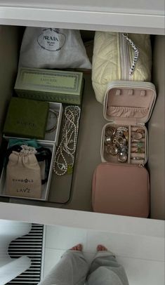 a woman's feet in front of an open suitcase filled with jewelry and other items