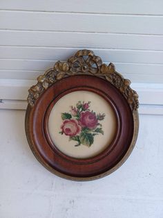 an old wooden frame with flowers painted on it hanging on the wall next to a door