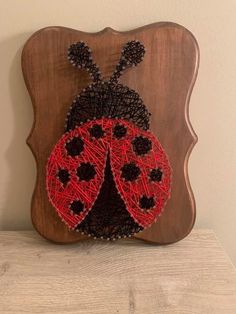 a wooden plaque with a red and black ladybug on it