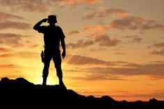 a man standing on top of a hill at sunset