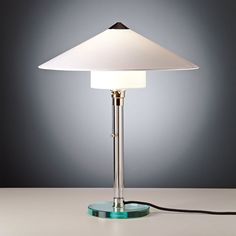 a table lamp with a white shade on it and a cord plugged into the base