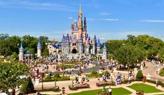 people are walking around in front of the castle at disneyland's magic kingdom park