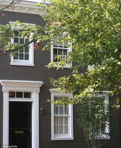 a black house with white trim on the front door and two windows in the side