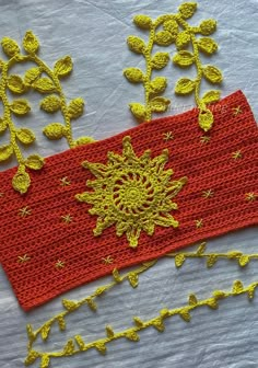 two crocheted headbands with yellow flowers and leaves on white cloth next to each other