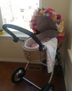 a baby's stroller with flowers on it in front of a window