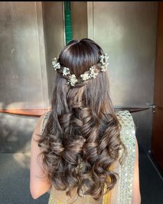 the back of a woman's head with long hair and flowers in her hair