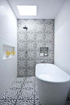 a white bath tub sitting next to a walk in shower under a skylight on top of a tiled floor