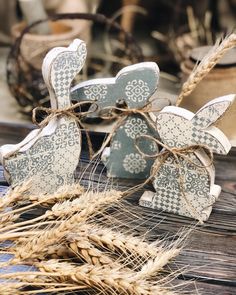 two wooden rabbits sitting on top of a table next to some ears of wheat in front of them