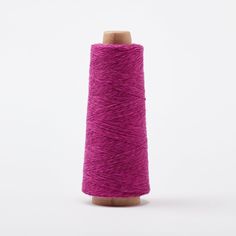 a spool of purple thread on a white background with a wooden stick in the foreground